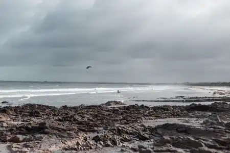 Un kitesurfer entre dans la mer sous un ciel de tempête