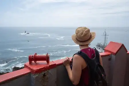 une femme regarde la mer d'Iroise depuis le phare de la pointe Saint-Mathieu