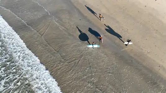 surfers sur la plage avec ombre chinoise en vue aérienne drone