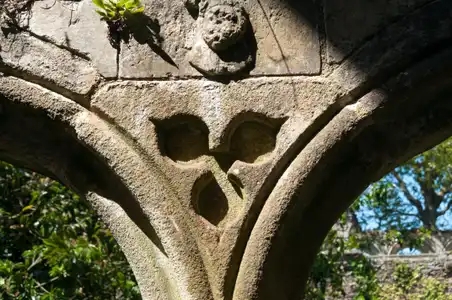 Gravure à trois feuilles entre deux arches en pierre dans l'Abbaye de Beauport