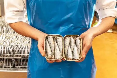 Sardines en boîte, dans la main d'une opératrice de production