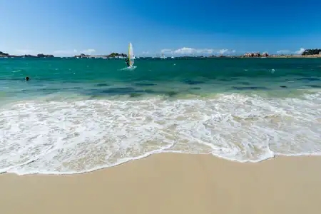 Planche à voile au bord d'une plage de sable blanc