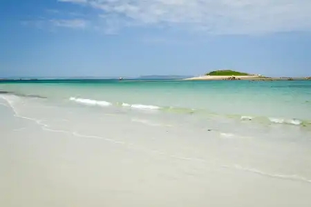 Plage de sable blanc paradisiaque et îlot au loin