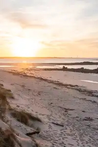 Le soleil se couche sur la plage du Curnic à Guissény, le phare de l'île vierge veille au loin
