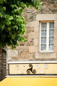 Triskel breton sur une façade de maison en pierre au-dessus d'un commerce