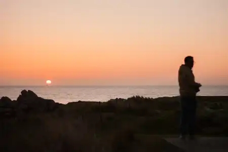 Un jeune homme se retourne devant le coucher du soleil au bord de mer