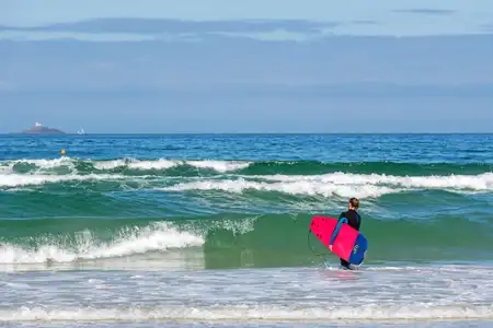 surfer femme entrant dans l'eau à la baie des trépassés