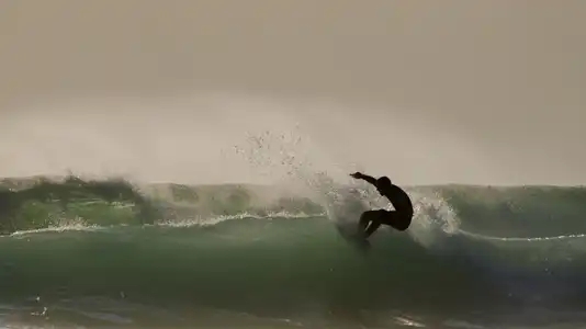 silhouette de surfeur sur une vague émeraude