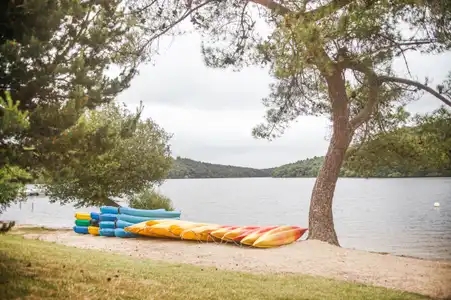 Club de Kayak entreposés sur le sable du lac de Guerlédan