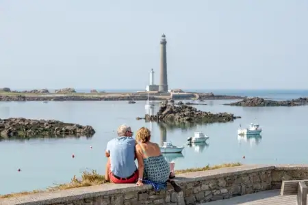 un couple de séniors devant le phare de l'île vierge à Plouguerneau