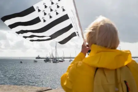 femme avec un ciré jaune et un drapeau breton