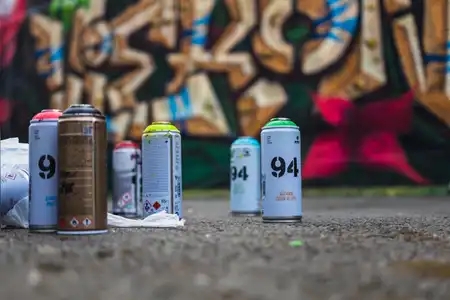 Des bombes de peinure devant un mur avec un graffiti