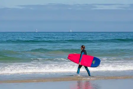 Surfer entrant dans l'eau avec sa planche