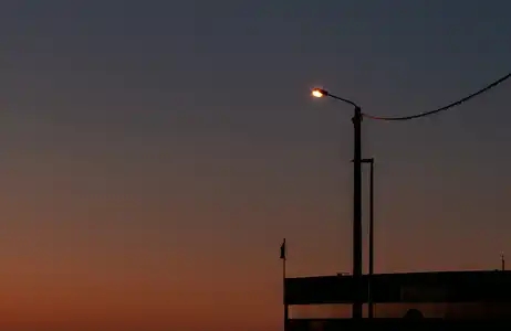 Un lampadaire s'allume au dessus d'un centre nautique à la tombée de la nuit