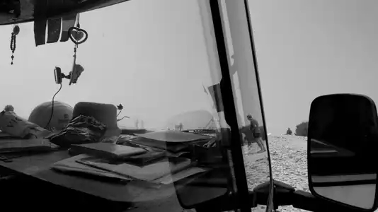 La plage de la Baie des Trépassés dans la brume, à travers la vitre d'un van, noir et blanc.