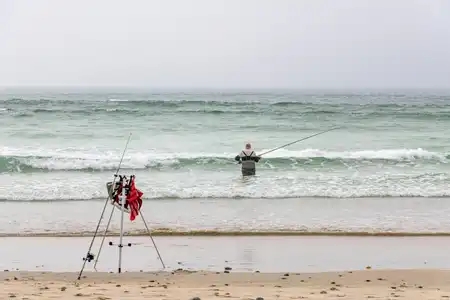 pêcheur surfcasting, dans l'eau sur la plage de la Torche Finistère