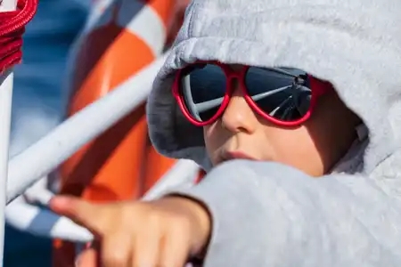 Enfant montrant l'horizon du doigt sur un bateau