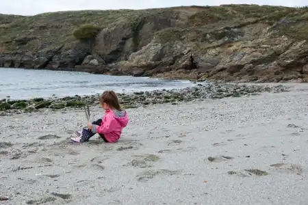 enfant sur la plage regarde l'océan