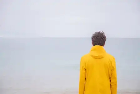 Personne en ciré jaune qui regarde la mer