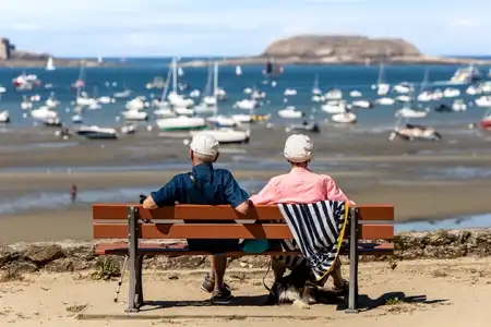 Un couple assis sur un banc contemple la mer