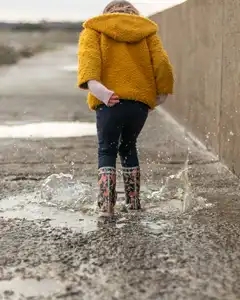 Petite fille saute dans les flaques sur une digue bretonne